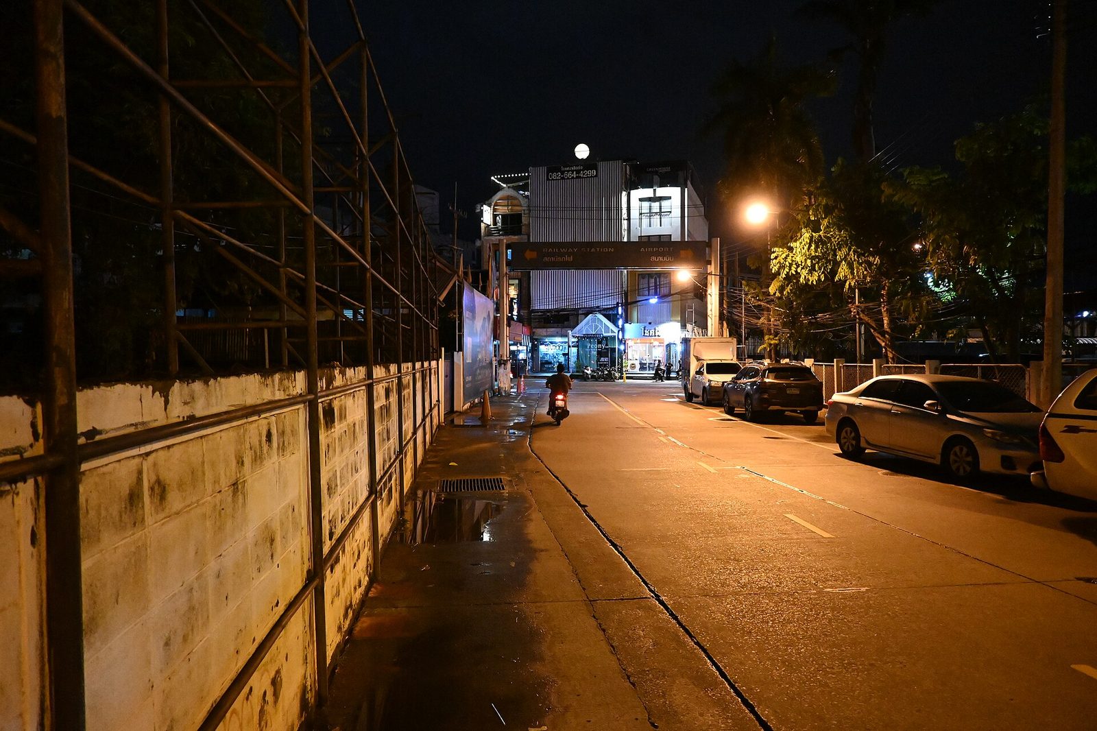 Rua urbana silenciosa à noite com carros estacionados sob os candeeiros